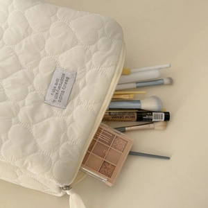 Close-up of heart-quilted toiletry bag showing soft fabric texture and inner storage