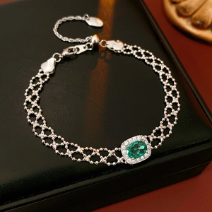 Detail of vintage silver beaded bracelet with oval green emerald and zircon halo setting