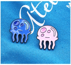 Macro detail of cute blue and pink enamel jellyfish pins on blue canvas texture