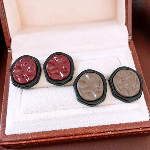 Macro detail of irregular textured earrings in burgundy and taupe with hexagonal frames