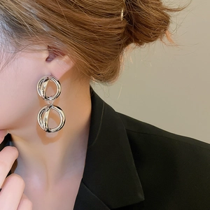 Primo piano di orecchini a cerchio intrecciati in argento indossati da una modella