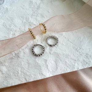 Makroaufnahme von S925 Sterling Silber Ohrsteckern in Gold und Silber auf weißem Stein