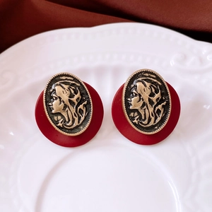 Detail of vintage earrings featuring copper-tone lady cameo on a red oval resin base