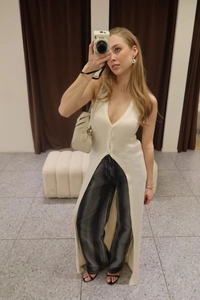 Mirror selfie showing a cream knit long vest with deep V-neck and high front slit