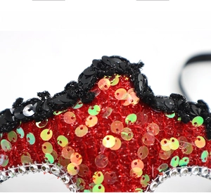 Close-up of red sequined masquerade mask featuring gold dragon patterns and rhinestones