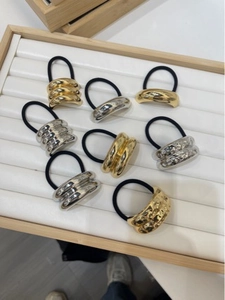 Detail of 8 gold and silver metallic alloy hair rings on a wooden display tray