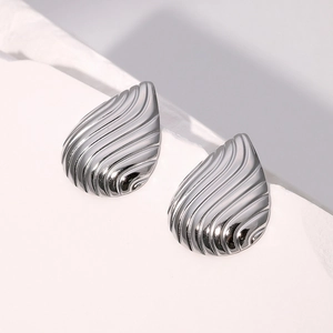 Détail macro de boucles d'oreilles goutte argentées avec texture ondulée et finition polie