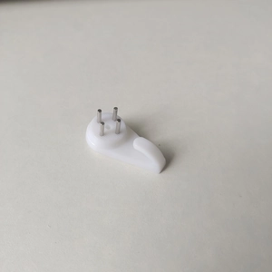 Close-up of a white plastic wall hook with three metal pins for seamless wall mounting