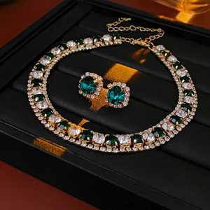 Detailed view of a gold necklace and earrings set with green gems and diamonds