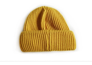 Detailed texture of ginger yellow ribbed knit beanie hat with stylish fabric label