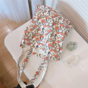 Detailansicht der Stofftasche mit orangefarbenem Blumendruck und Webetikett auf Tisch