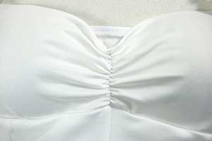 Close-up of ruched center detail on a white backless halter mini dress fabric