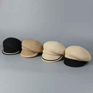 Flat lay of woven straw newsboy caps in black brown beige and cream with striped brims