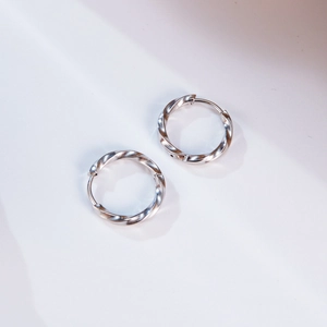 Close-up of silver stainless steel twisted hoop earrings with a geometric Mobius design