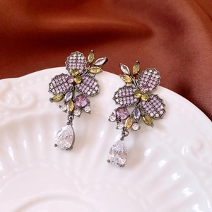 Dettaglio macro di orecchini vintage con zirconi colorati su un piatto di ceramica