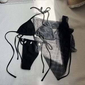 Detail of black mesh bikini set with natural white shell charms and matching sarong cover-up