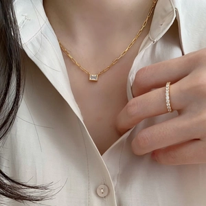 Close-up of elegant gold rectangle gemstone necklace and matching ring on model