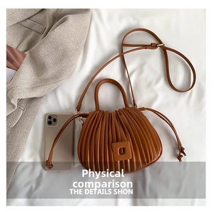 Detailed top view of a brown pleated bucket bag with PU leather texture and shoulder strap