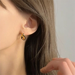 Close-up of elegant gold twisted hoop earring worn by a model in a minimalist style