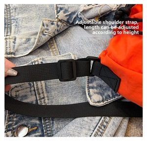 Detail of adjustable black nylon strap on an orange bucket bag with buckle feature