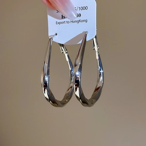 Macro shot of twisted silver metal teardrop earrings with a polished mirror finish