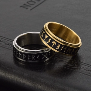 Macro detail of Nordic rune engravings on gold and silver stainless steel spinning rings