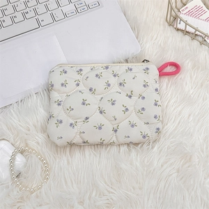Detailed close-up of a quilted floral mini makeup bag with a pink woven zipper puller