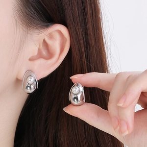Detail of silver water-drop earrings with white pearl inlay and polished metal finish