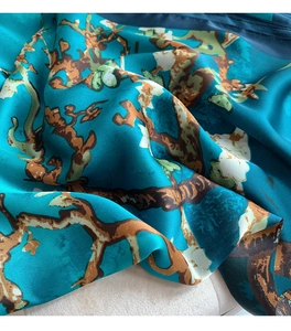 Macro detail of silk scarf featuring Van Gogh almond blossom print on teal blue fabric
