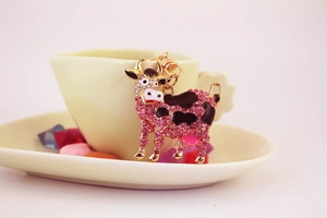 Close-up of golden cow keychain with sparkling pink rhinestones and black enamel accents