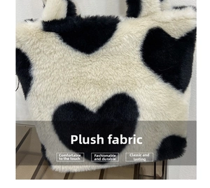 Close-up of soft plush tote bag featuring black heart patterns on creamy white faux fur