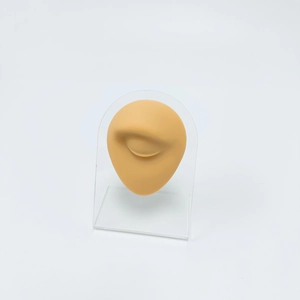 Beige silicone eye model on acrylic stand for makeup and medical piercing practice