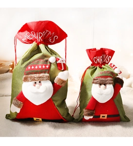 Detail of green fabric Christmas gift bags with red drawstring and Santa Claus ornaments