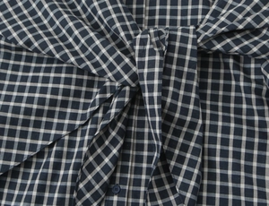 Detail of checkered shirt showing waist tie knot and classic plaid fabric texture