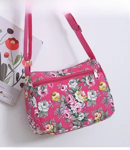 Close-up of pink floral crossbody bag with metal zipper pocket and adjustable strap
