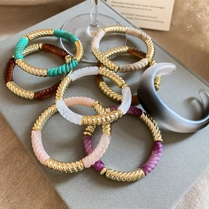 Close-up of twisted acrylic link bracelets and gradient resin bangle on a display stand