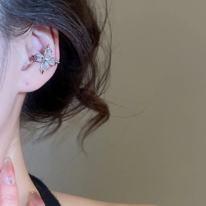 Detailed macro view of a silver cross star ear cuff set with sparkling zircon stones