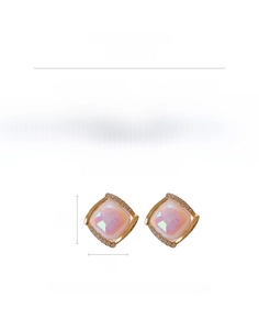 Macro shot of square stud earrings with iridescent pink centers and crystal halos