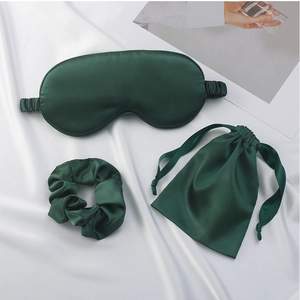 Detail showing dark green satin sleep mask set with matching scrunchie and drawstring pouch
