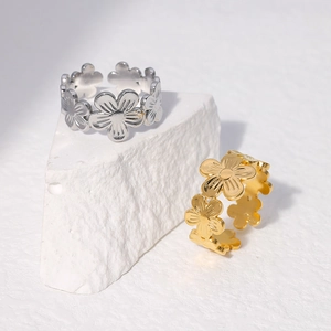 Detailed view of silver and gold flower-patterned stainless steel rings on a stone