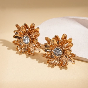 Macro shot of gold-plated daisy earrings with sparkling central zircon and textured petals