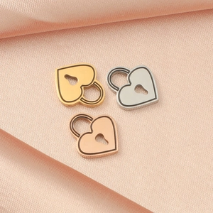 Three mirror-polished heart padlock pendants in gold, silver, and rose gold on pink satin