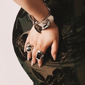 Close-up of a model wearing a wide silver stainless steel bangle and two unique fashion rings