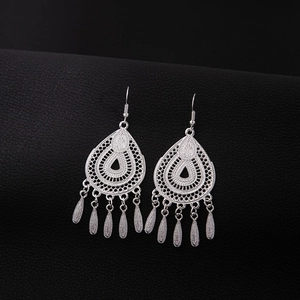 Macro view of vintage silver drop earrings with hollow teardrop frame and leaf tassels
