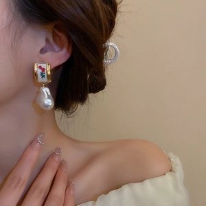 Close-up of vintage floral earrings with silver pins and pearls worn by a model