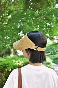 Detail of adjustable khaki elastic strap and silver buckle on raffia sun visor hat