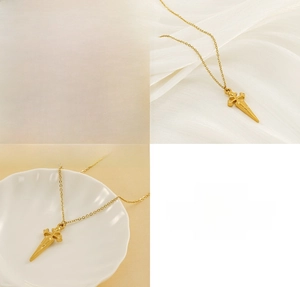 Detailed view of a gold sword cross pendant necklace in stainless steel on silk