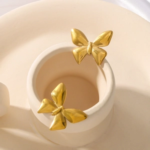 Elegant 18K gold plated bow-shaped titanium steel stud earrings on ceramic background