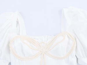 Detail of square neckline with beige woven rope knot decor and puff sleeve fabric texture