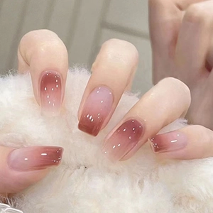 Close-up of pink blush gradient press-on nails on model holding a white plush ball